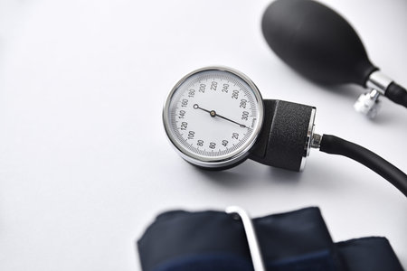 Detail of manual blood pressure monitor with blue cuff isolated on white table. Top view.