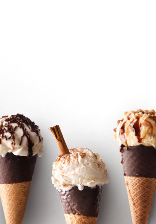 Detail of three ice cream cones of various flavors with chocolate cones on white background. Vertical compositionの写真素材