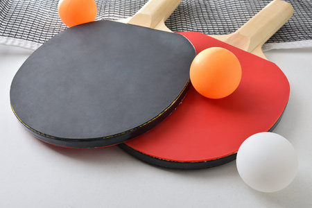 Background with set of table tennis paddles, net and orange ball isolated on white table. Elevated view.の写真素材