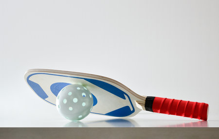 Background of pickleball paddle on ball reflected on white table and white isolated background. Front view.の写真素材