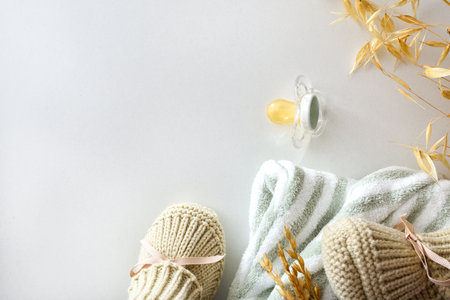 Baby beige fabric booties isolated on white table with striped blanket pacifier and ears. Top view.の写真素材