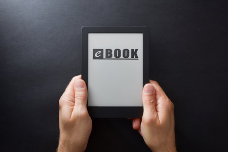 Hands holding an ebook with text on screen and black isolated background. top viewの写真素材