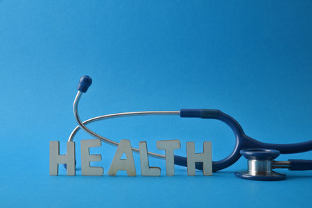 Health background with stethoscope and health message with wooden letters on blue background. front viewの写真素材