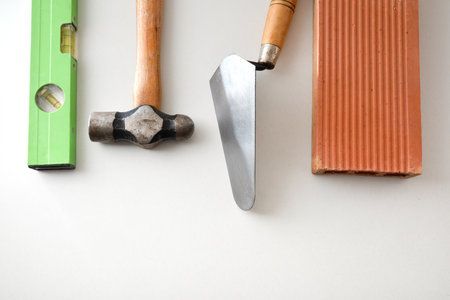 Construction tools such as trowel, level, hammer and brick isolated on white background. Top view.の写真素材