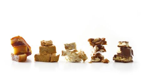 Row with piles of various nougats of different flavors with almond, chocolate, and caramel, and others isolated on a white background. Front view.の写真素材
