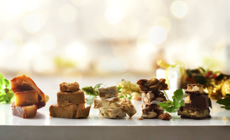 Selection of Christmas nougats of various flavors piled up in portions in a row on a white table with Christmas decoration and atmosphere. Front view.の写真素材