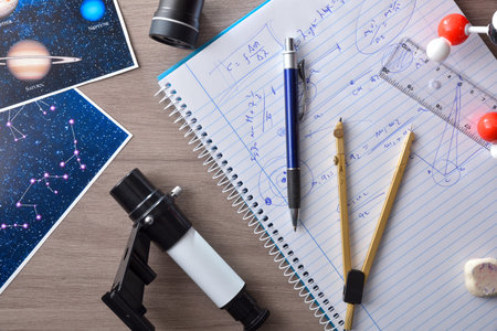 Detail of the study in astronomy with a wooden table with a notebook with analysis formulas, a pen,...