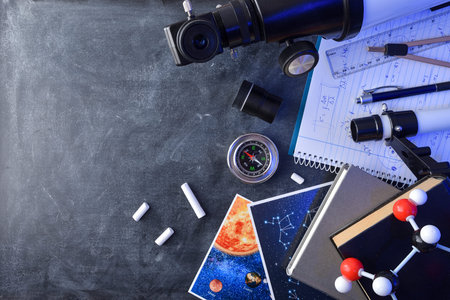 Educational material photos and telescope for the study of astronomy on a blackboard with chalk. Top...
