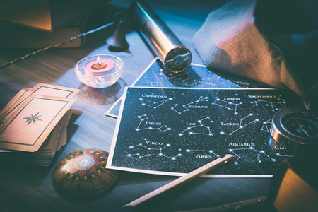 Esoteric astrological background detail with map with constellations, divination cards and retro objects on wooden table with magical atmosphere. Elevated view.の写真素材