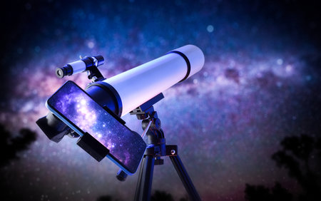 Detail of a telescope outside pointing at a star filled sky with a phone holder and mobile phone with screen showing the magnification of the telescope.の写真素材