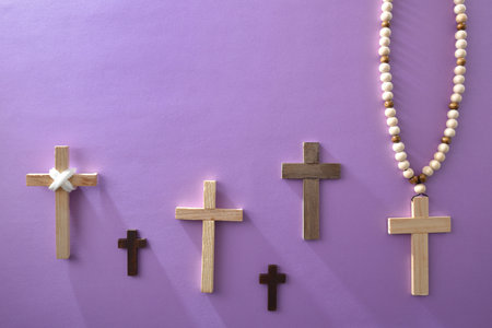 Group of basic wooden Christian crosses of different shades and sizes with and without bead pendants on a lilac background. Top view.の写真素材