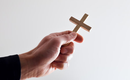 Detail of man holding religious wooden cross with white isolated background.の写真素材