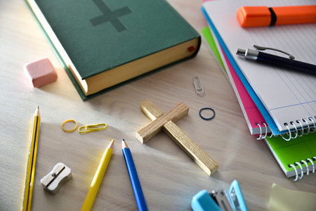 Religious education concept with a crucifix in the center of a wooden table with educational...