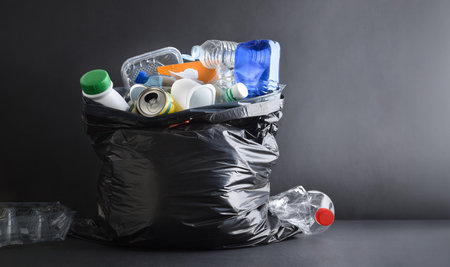 Background with detail of black plastic garbage bag full general waste isolated on dark background and base. Front view.の写真素材