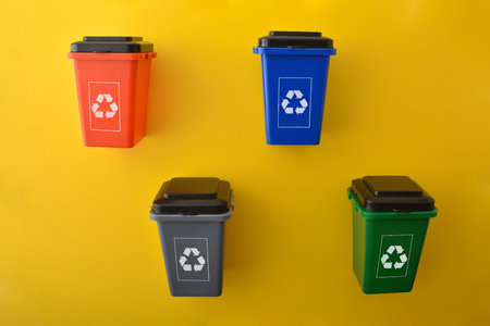 Set of multi-colored recycling bins with multi-colored recycling symbol isolated on yellow base. Top view.の写真素材