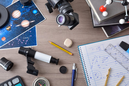 Astronomy student workspace concept with wooden bench filled with items for astronomical study such...