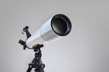Detail of the main lens of a white telescope with eyepiece and finder scope mounted on black tripod isolated on white gradient background. Front view.の写真素材