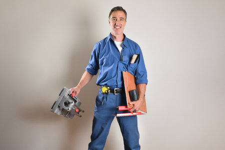 Tiler in work clothes smiling with ok gesture holding tools on isolated background. Front view.の写真素材