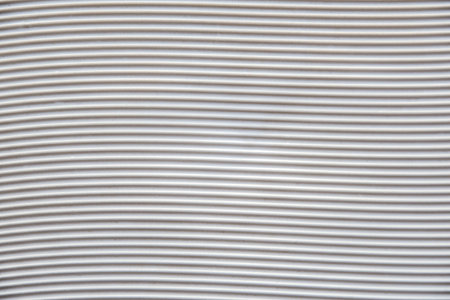 Background with a white plastic base with grooves forming horizontal waves. Top view.