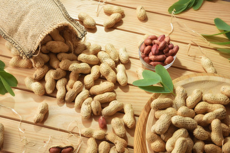 Wooden table with bowls, plates, and a sack full of freshly picked peanuts. Top view.