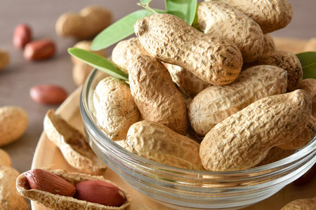 Macro view of group of peanuts with shell in glass bowl on a wooden plate on wooden bench decorated...