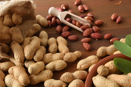 Detail of a peanut on a rustic wooden table with shells and peeled nuts in various containers....