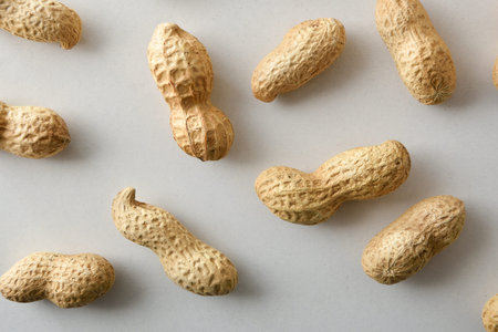 Detail of several peanuts in shell showing their shape and texture on a white table. Top view.