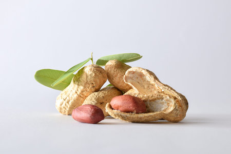 Detail of a group of peeled and unpeeled peanuts with leaves isolated on white background. Front...