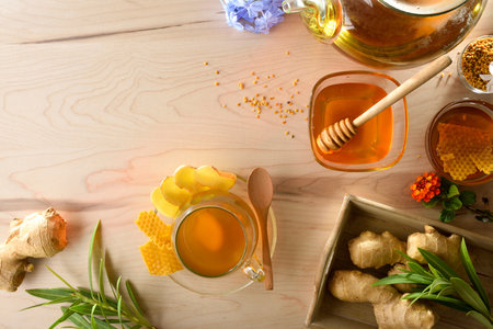Freshly prepared ginger and honey infusion on a wooden bench with ginger roots, jars of honey flowers and decoration. Top view.の写真素材