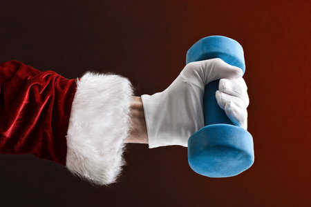 Hand in suit and gloves lifting a blue dumbbell on red isolated background.の写真素材