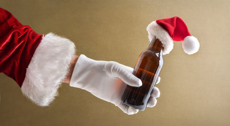 Santa Claus hand in suit and glove with bottle of beer in hand decorated with Santa hat with isolated backgroundの写真素材