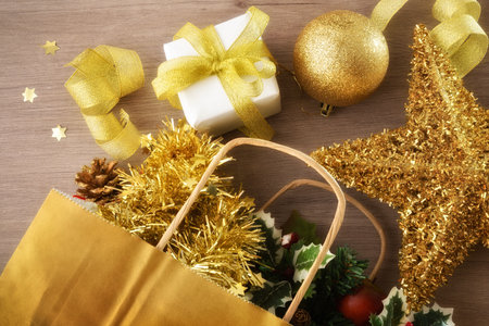 Detail macro of christmas gift concept with a bag full of gifts and Christmas decorations on a wooden table. Top view.の写真素材