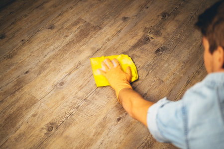 young man clean the floor with a yellow cloth