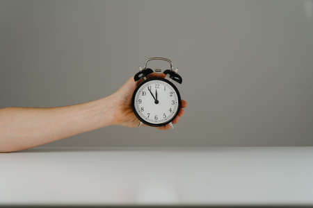 Hand holding black alarm clock eleven fifty-fiveの写真素材