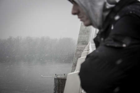 Sad man enjoying the view from a bridge in winter.の写真素材