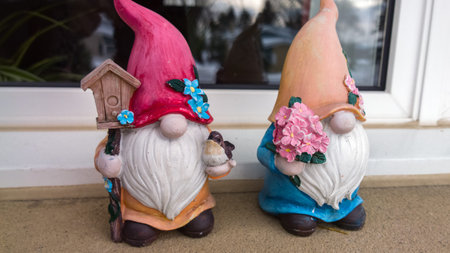 Two ceramic garden gnomes with flowers on the windowsill