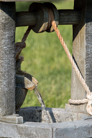 Close up of a water well with a rope in the background.の写真素材
