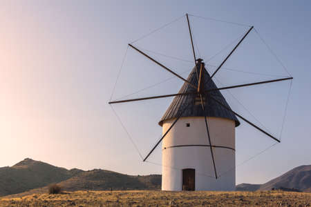 Windmill at sunset between the hills of the natural park of Cabo de Gata in southern Spain. Almeria, Andalucia. Mediterranean Seaの写真素材