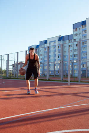 Guy plays basketball on a red Court.の写真素材