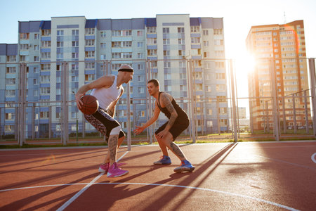 Two guys jump stretch to the ball on the basketball court.の写真素材
