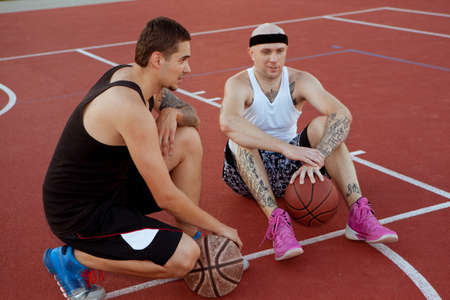 Two guys are sitting on the basketball court.の写真素材