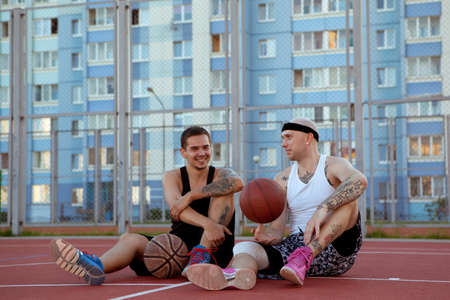 Two guys are sitting on the basketball court.の写真素材
