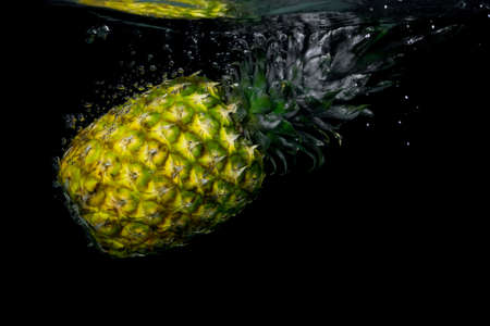 Pineapple falling in water on black background watchの写真素材