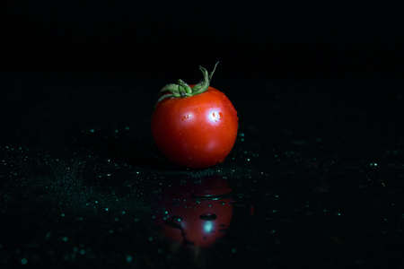 Fresh tomato with water drops isolated on black backgroundの写真素材