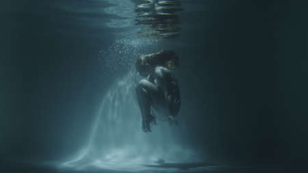 underwater gymnastics of a beautiful girl in a white dressの写真素材