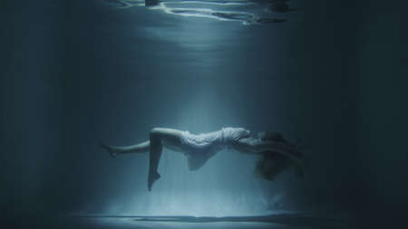 girl in a white dress swims underwaterの写真素材