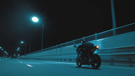 A man rides a sports motorcycle on a night trackの写真素材