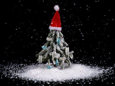 Beautiful Christmas tree with red hat and masks. 2021 Coronavirus concept. Snowing dark background....