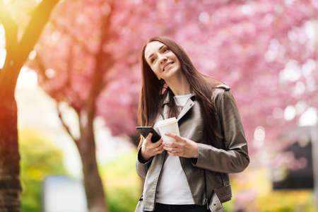 Womens beauty and fashion. Urban lifestyle. girl on the background of pink flowering trees. Closeup portrait of girl in springの写真素材