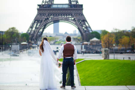 Bride and groom having a romantic moment on their wedding day in Paris, in front of the Eiffel tourの写真素材
